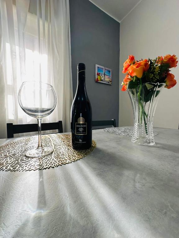 a bottle of wine and a glass and flowers on a table at Ferdirisa Vesuvio Home&Garden in San Giorgio a Cremano