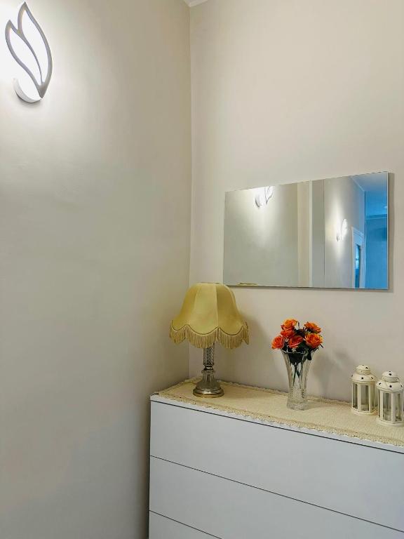 a lamp on a dresser with a mirror and flowers at Ferdirisa Vesuvio Home&Garden in San Giorgio a Cremano