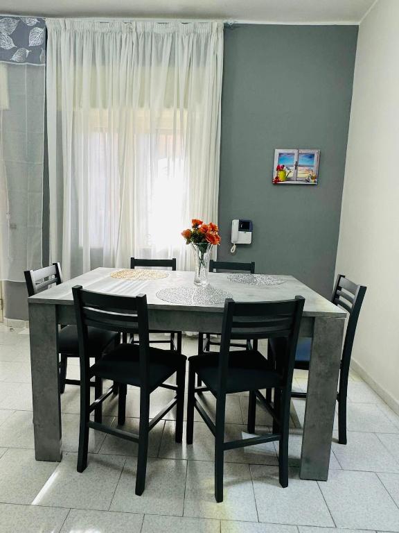 a dining room table with chairs and a vase of flowers at Ferdirisa Vesuvio Home&Garden in San Giorgio a Cremano