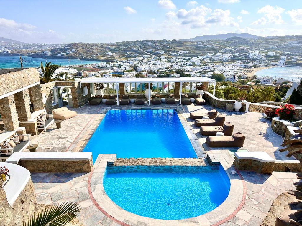 una piscina con sillas y vistas al océano en Leonis Summer Houses, en Ornos