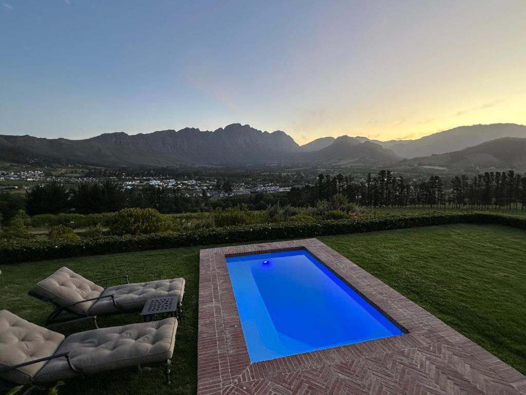 a swimming pool in the middle of a lawn with two chairs at The Vineyard Cottage by L' Amitie Estate in Franschhoek