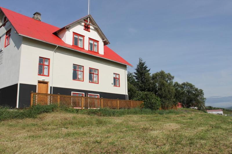 une grande maison blanche avec un toit rouge sur une colline dans l'établissement Geitaskarð, à Blönduós