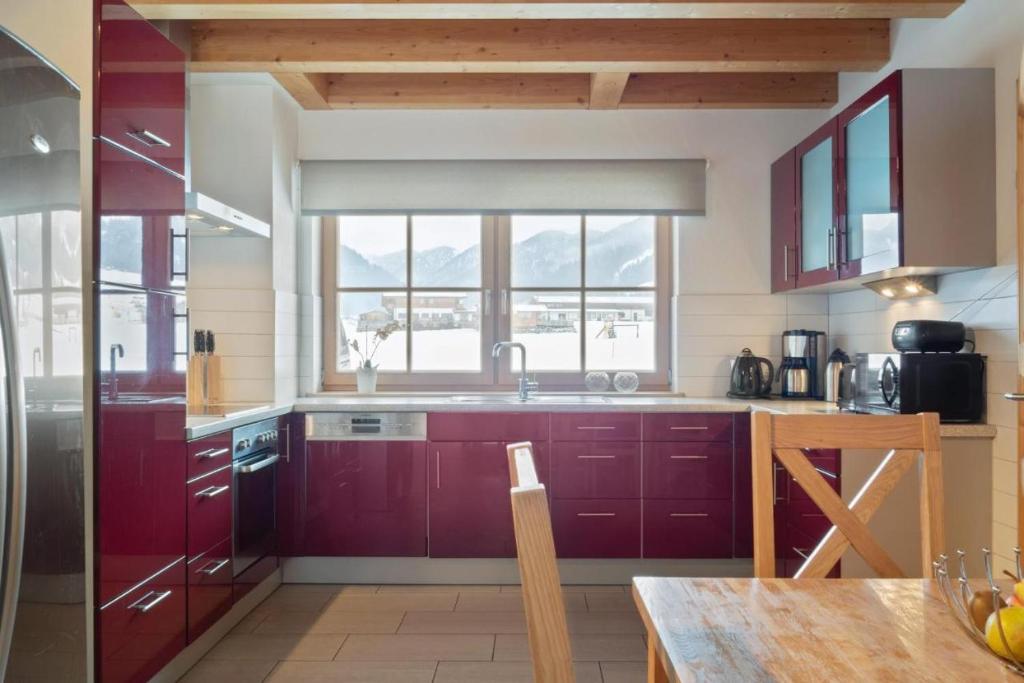 cocina con armarios rojos y ventana grande en Chalet Maxima en Sankt Jakob in Haus