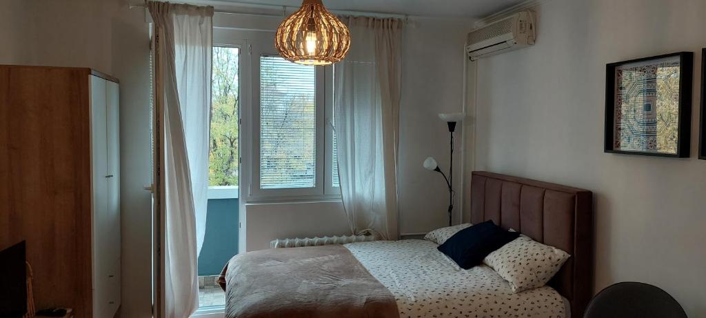 a bedroom with a bed and a window and a chandelier at Azulejo Apartment in Novi Beograd