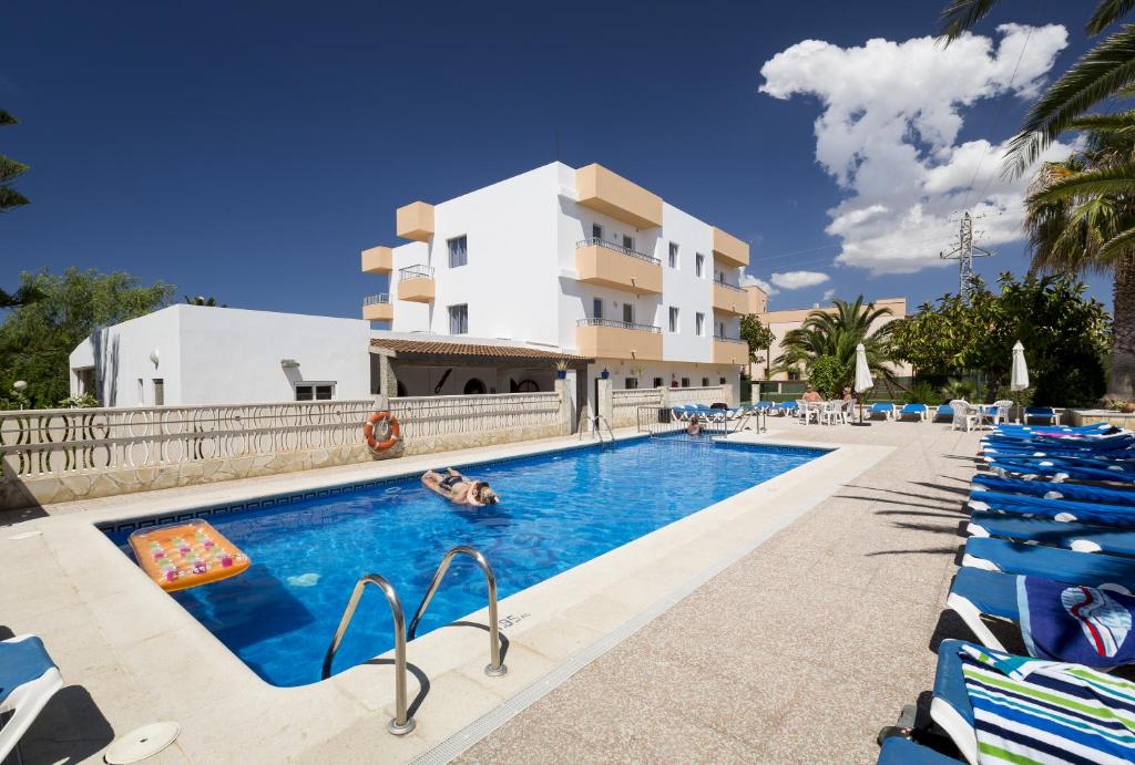 a hotel swimming pool with lounge chairs in front of a building at Apartamentos Zodiac in San Antonio Bay