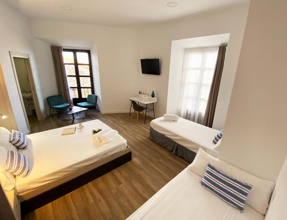 a hotel room with two beds and a television at Hostel Casa Vargas Figueroa in Cáceres