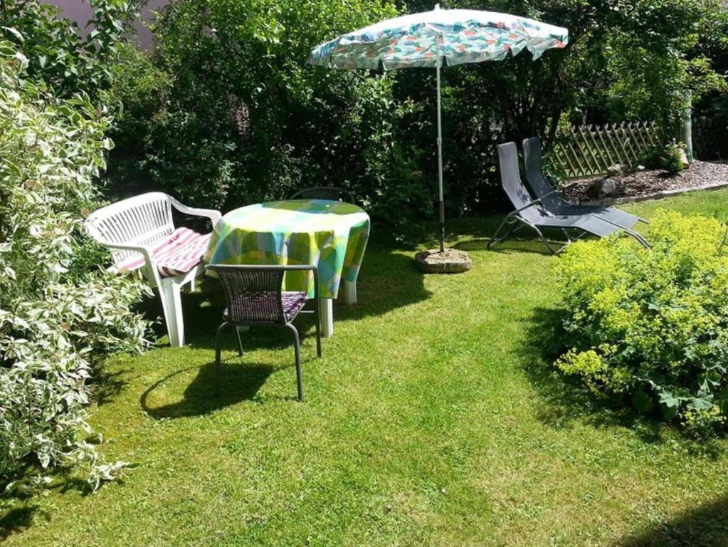 uma mesa e cadeiras e um guarda-sol num quintal em Schwalm - Aue em Neuental