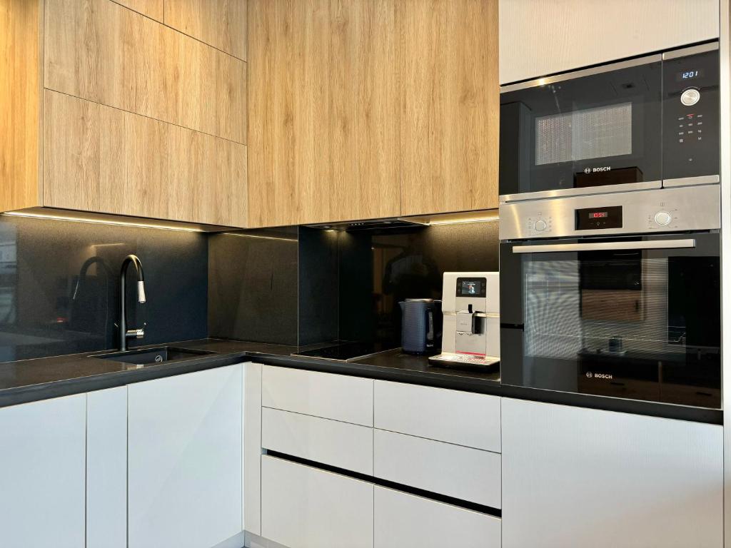 eine Küche mit weißen Schränken und schwarzen Geräten in der Unterkunft City Modern & Classy Apartment for 4 Guests & Parking in Sofia