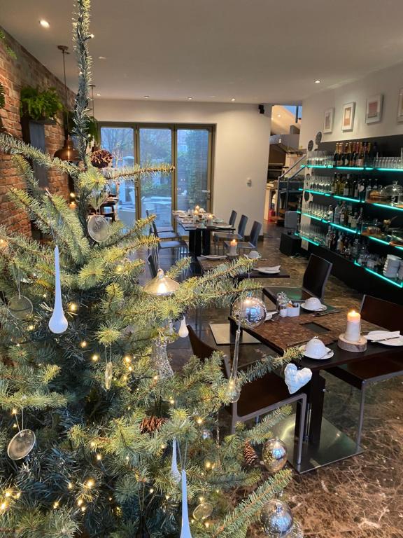 a christmas tree in a room with tables and chairs at The Rooms Lytham in Lytham St Annes