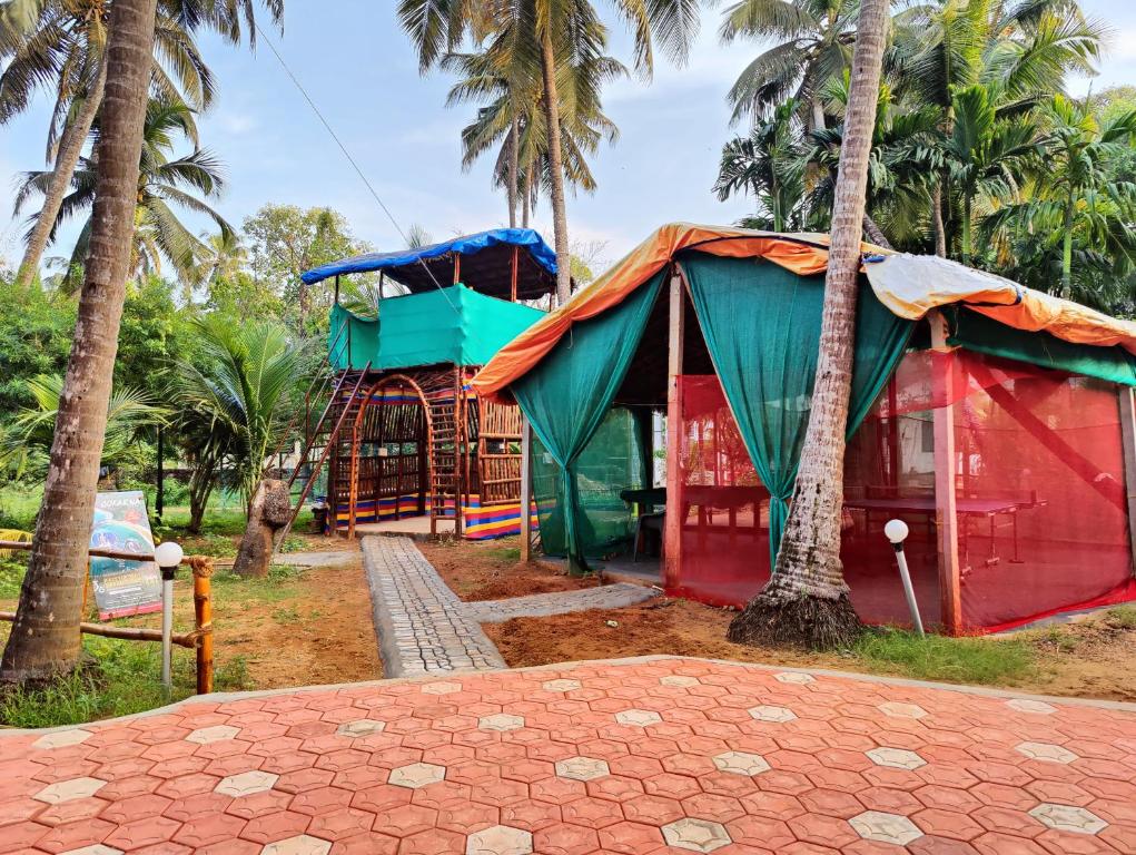 a small red and green building next to palm trees at ArtKarna in Gokarna