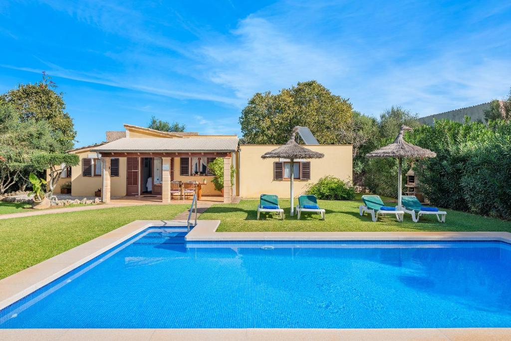a pool in front of a house with chairs and umbrellas at Villa Llompart Pollensa by JS Villas in Pollença