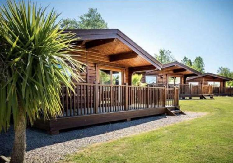 una cabaña de madera con una valla en un patio en Bishops Park Lodges At Fingle Glen Golf Club en Exeter