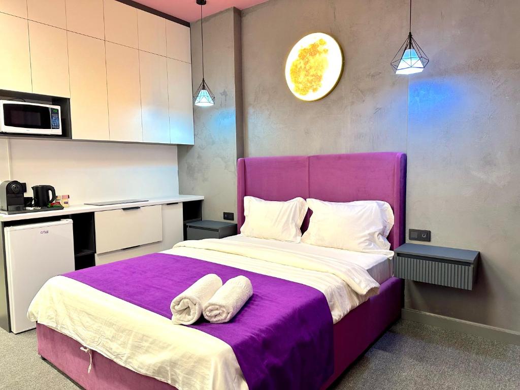 a bedroom with a purple bed with two towels on it at Apartments Almatau in Taldykolʼ