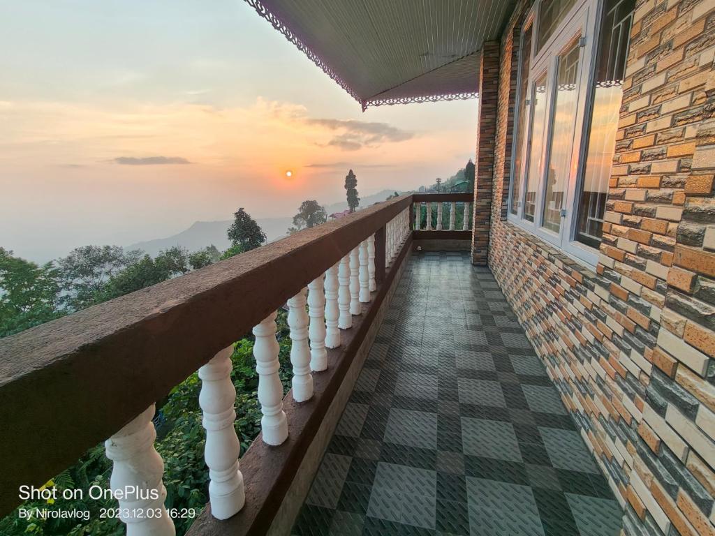a balcony of a house with a view of the sunset at RKD HOMESTAY in Kurseong