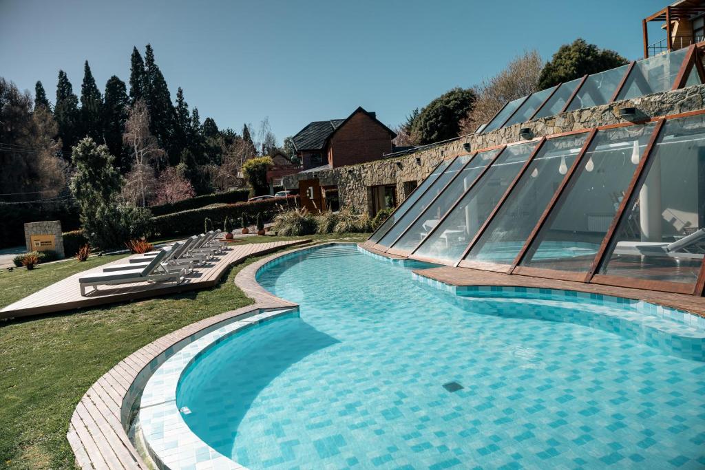 a swimming pool next to a house with a building at Rochester Bariloche Suites & Spa in San Carlos de Bariloche