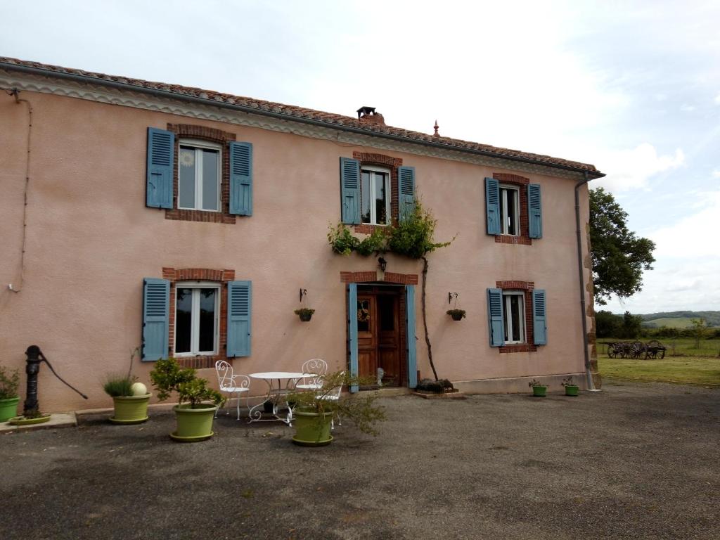 ein Haus mit blauen Fensterläden und einem Tisch in der Unterkunft Le Chapelat in Saint-Michel-Saint-Jaymes