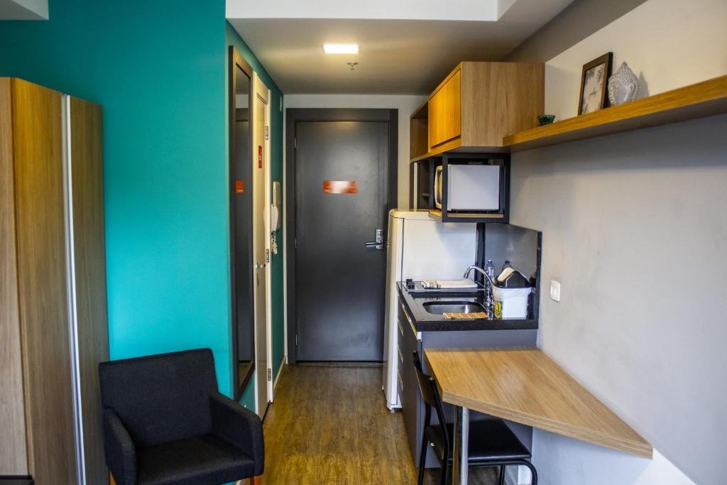 a small kitchen with a counter and a refrigerator at Studio no centro de Curitiba in Curitiba