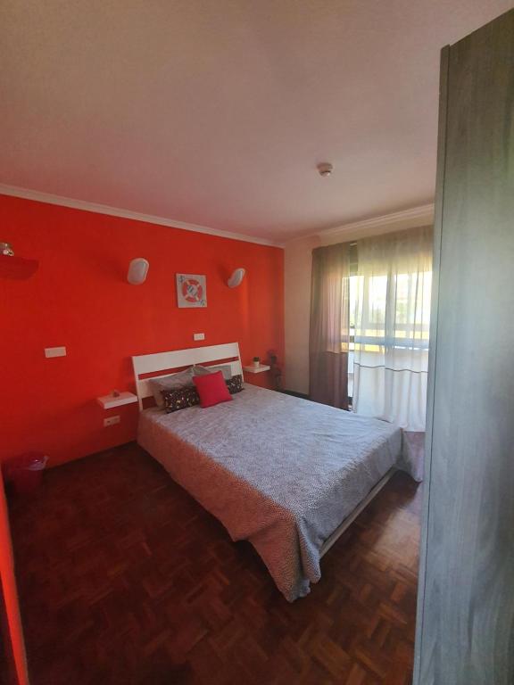 a bedroom with a bed with red walls and a window at Hospedagem Emanuel in Caneças