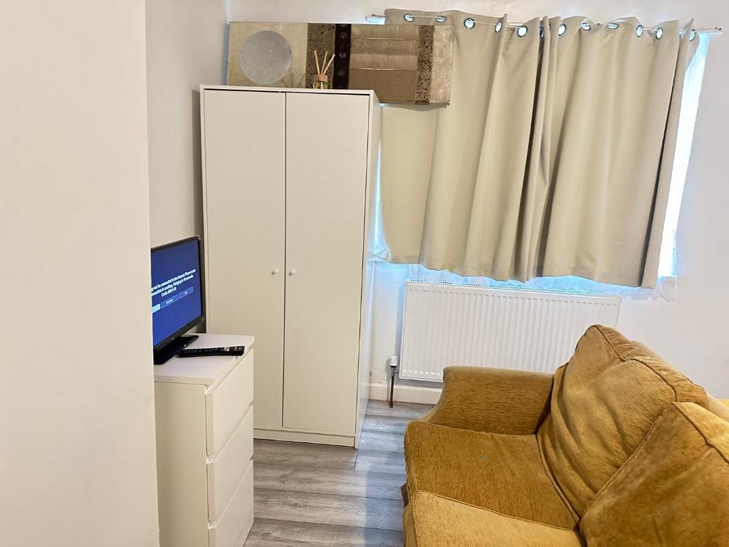 ein Wohnzimmer mit einem Stuhl und einem TV in der Unterkunft Ebehi Inn in London