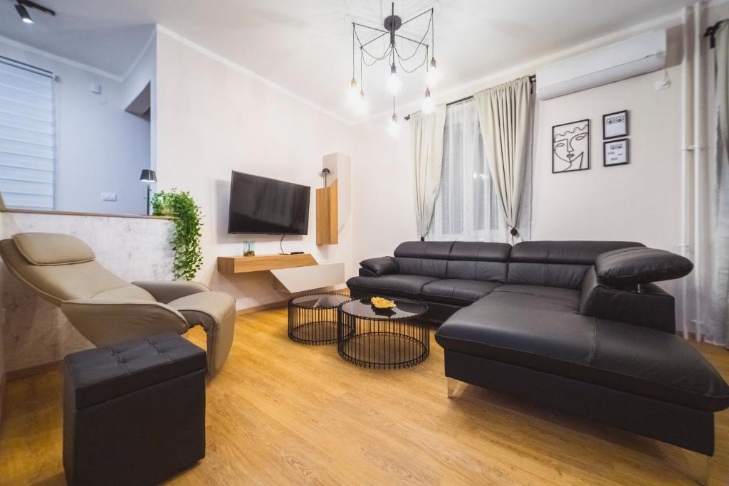 een woonkamer met een zwarte leren bank en stoelen bij Luka's apartment in Pirot
