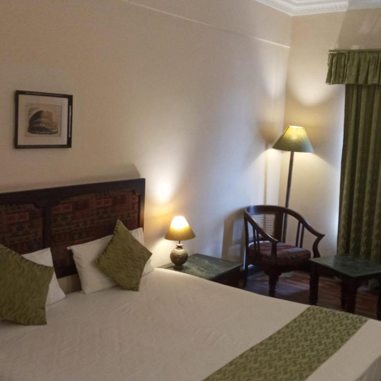 a bedroom with a bed and a chair and a lamp at THE WYTE FORT in Cochin