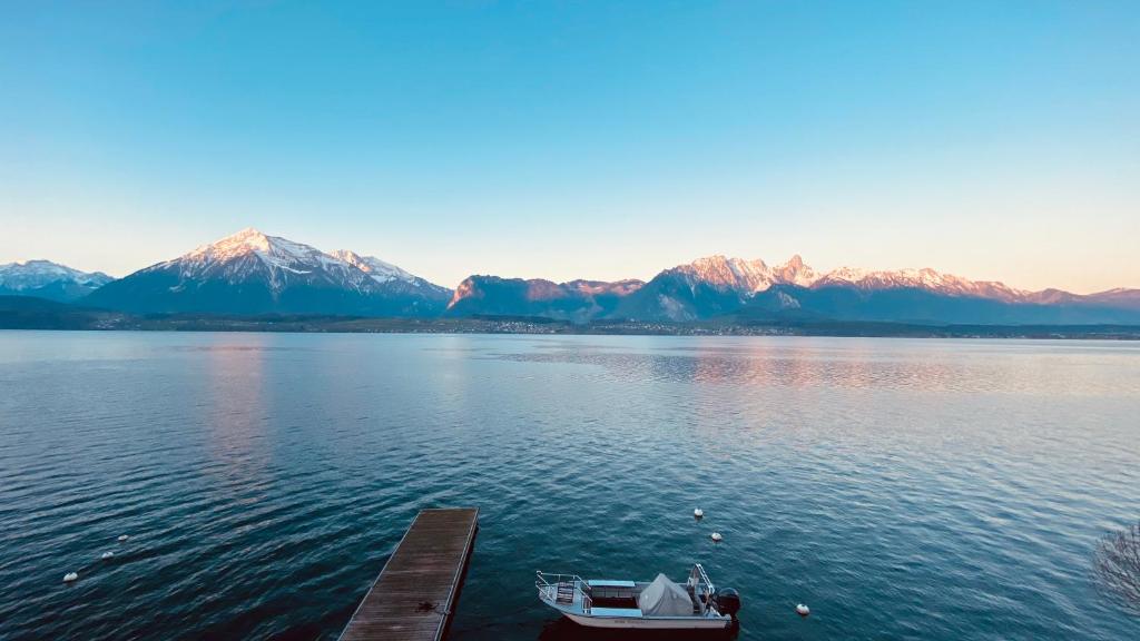 a boat on the water with mountains in the background at Dependance Stella del Lago by Hotel Restaurant Bellevue au Lac in Thun