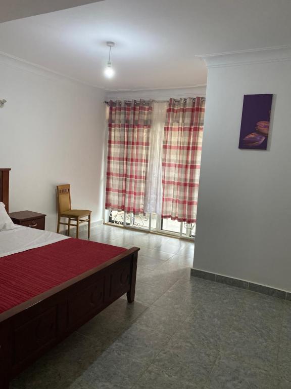 Namugongo的住宿－Ingrid's Place - Namugongo，一间卧室配有床和两个带窗帘的窗户