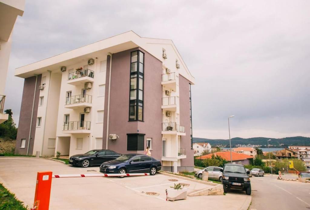 een groot gebouw met auto's geparkeerd op een parkeerplaats bij Sunny apartment in Tivat in Tivat