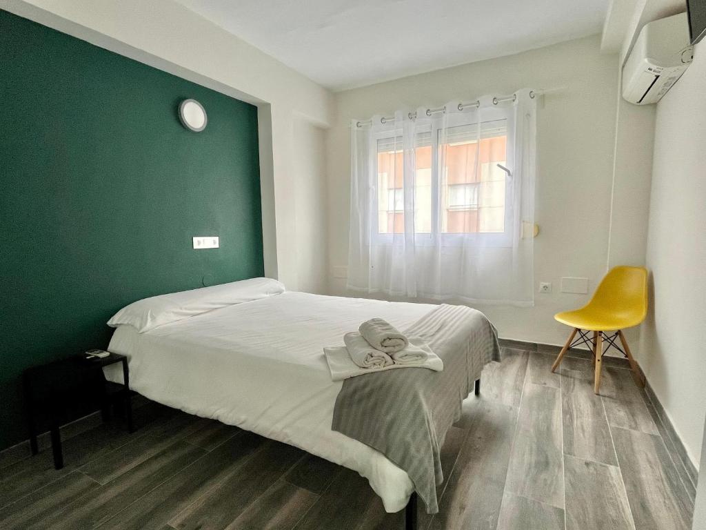 a bedroom with a bed and a yellow chair at New Click & Room in Torremolinos