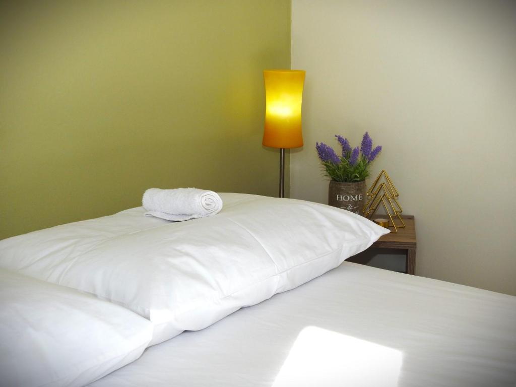 a bedroom with two beds with white sheets and a lamp at Melia Luxury Studio in Thessaloniki