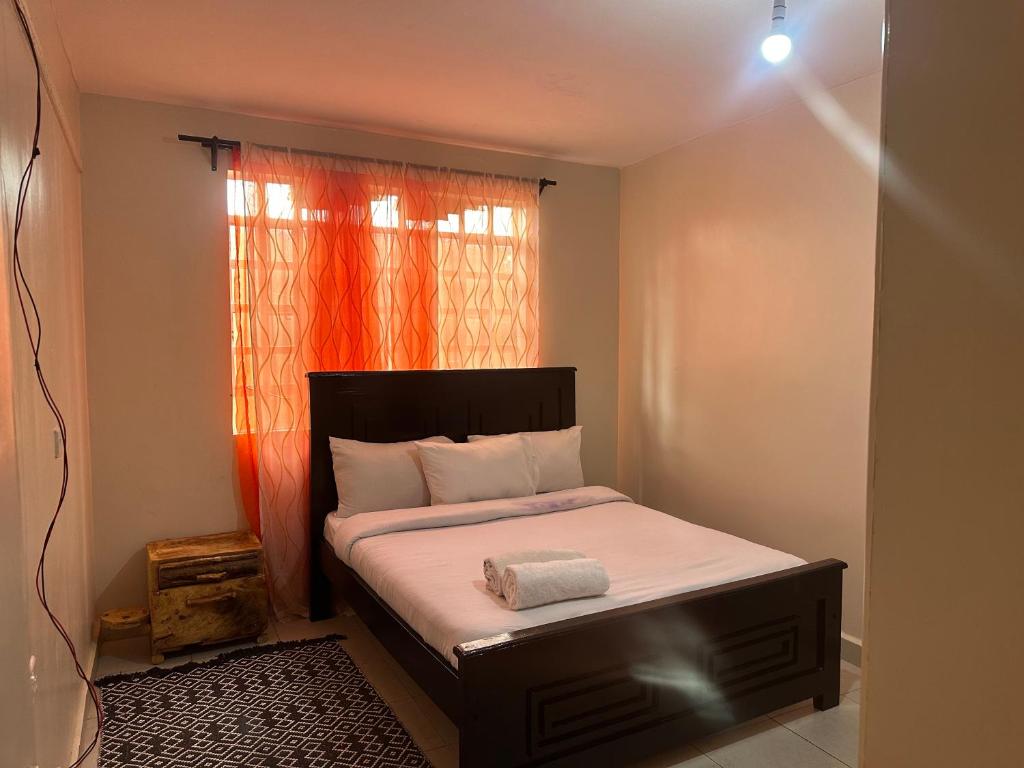 a small bedroom with a bed with an orange curtain at J L appartment in Eldoret