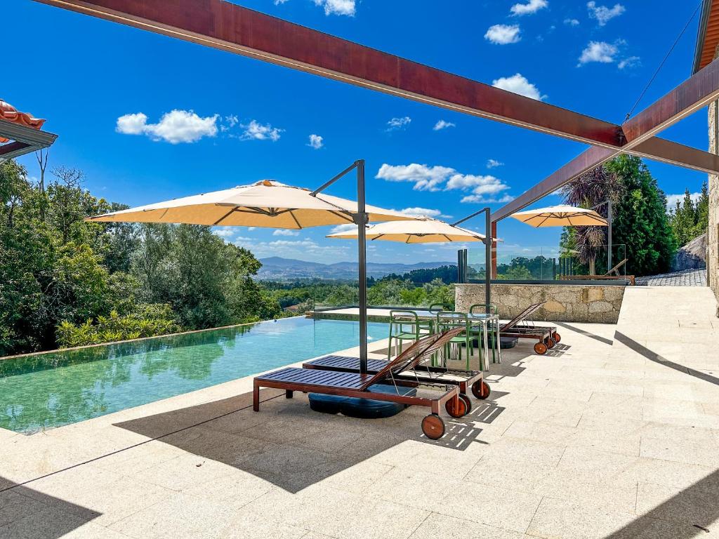 two lounge chairs and umbrellas next to a pool at Villa Isobel in Vila Verde