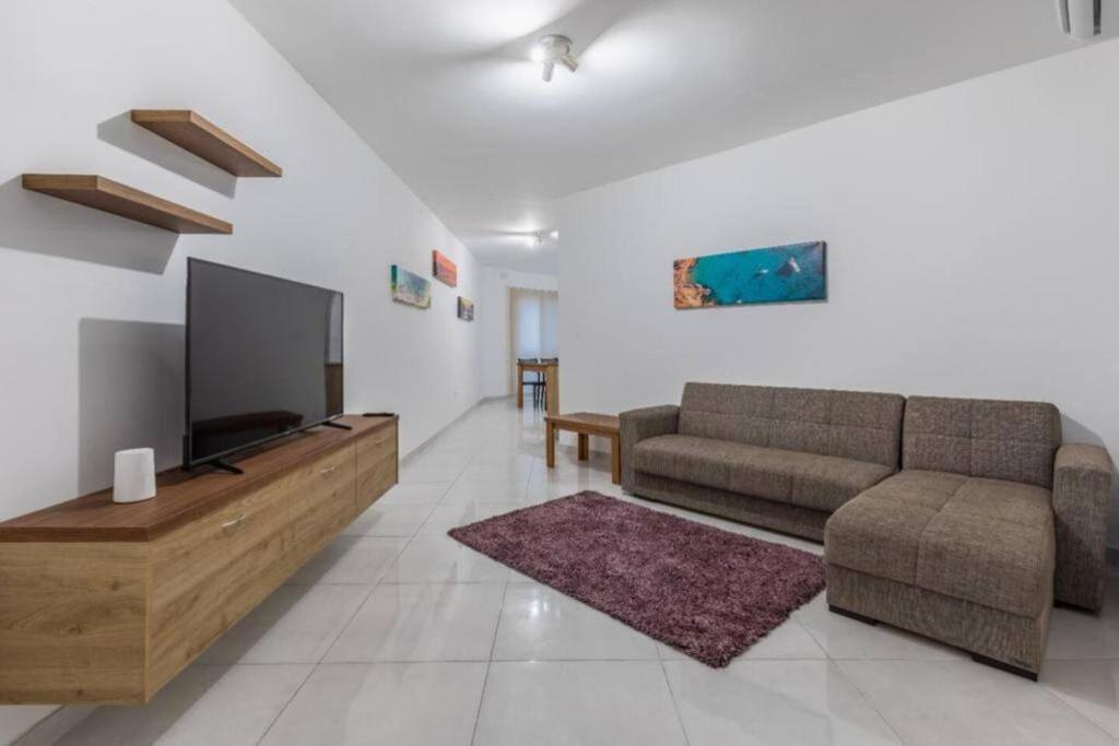 a living room with a couch and a flat screen tv at Marsaxlokk Two Bedroom Apartment 1 minute away from the seafront in Marsaxlokk