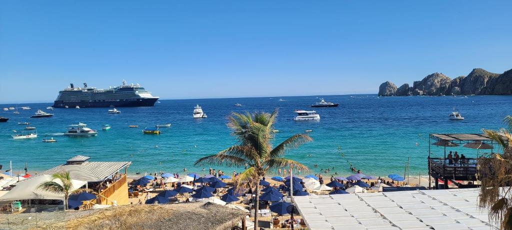 a group of people on a beach with a cruise ship at Ocean View Suites at Corazon Resort in Cabo San Lucas