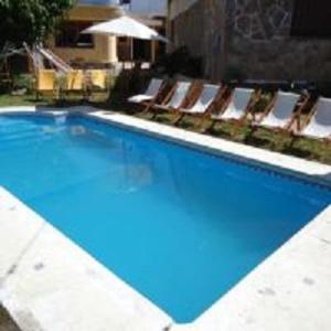 a large swimming pool with chairs and a swimming pool at Hotel El Nogal La Falda in La Falda