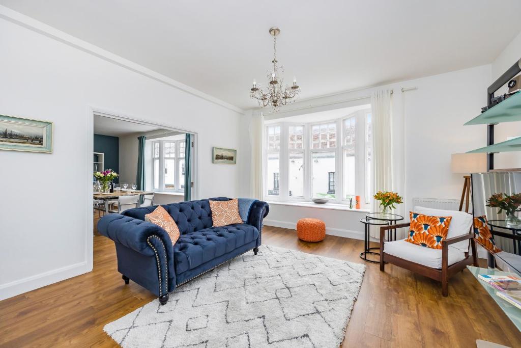 a living room with a blue couch and a chair at Ascot House Apartment in Hurstpierpoint