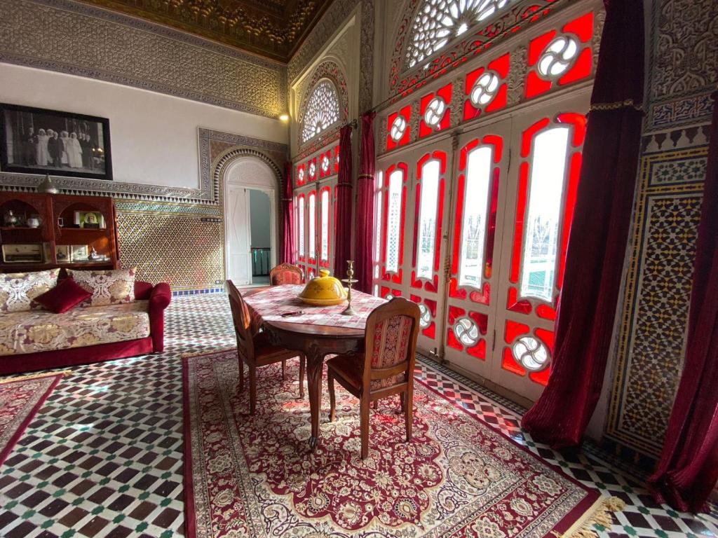 uma sala de jantar com mesa, cadeiras e janelas em Youssef em Fez