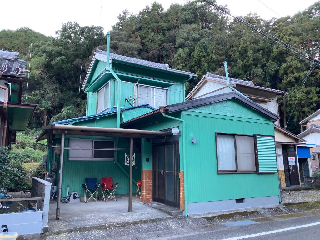 una casa azul y verde al lado de una calle en おばあちゃんち, 