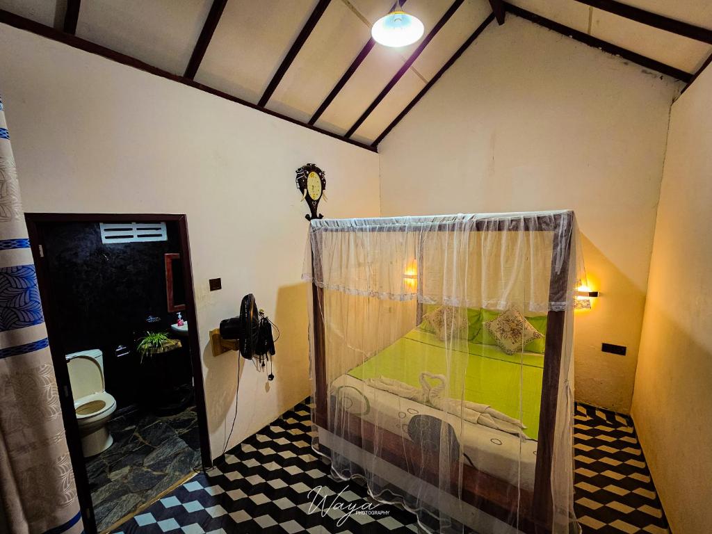 a room with a bed with a curtain in a bathroom at Peacock's Paradise Safari Hostel in Udawalawe