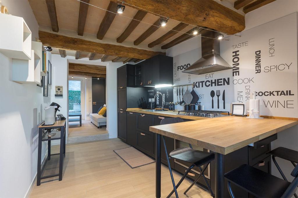 une cuisine avec des armoires noires et un comptoir en bois dans l'établissement MaRì Modern Flat - Nel cuore verde di Perugia - Posto Auto, à Pérouse