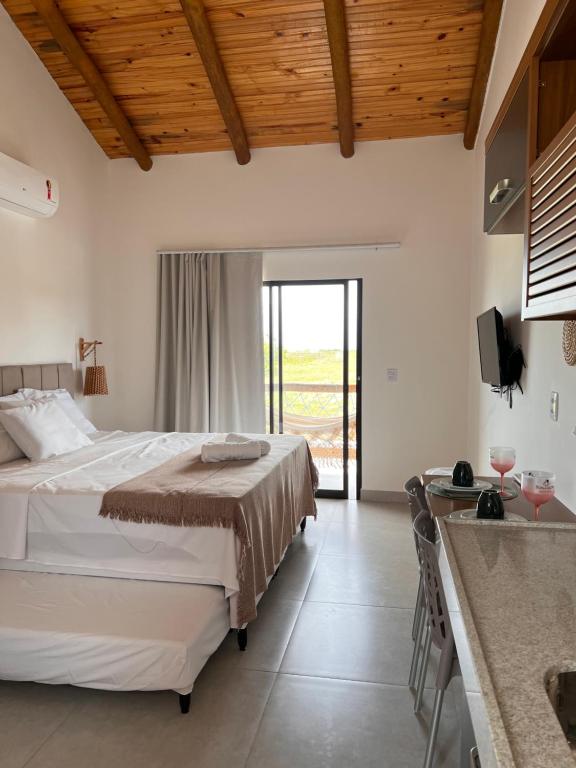 a bedroom with a bed and a kitchen with a television at Flor de Cacto Beach Home in São Miguel do Gostoso