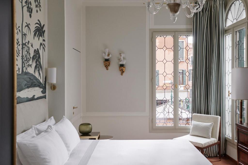 a bedroom with a bed and a chair and windows at Violino d'Oro Venezia in Venice