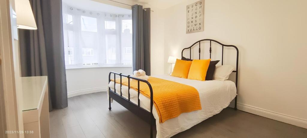 ein Schlafzimmer mit einem Bett mit orangefarbenen Kissen und einem Fenster in der Unterkunft Woodfield apartment in The Hyde