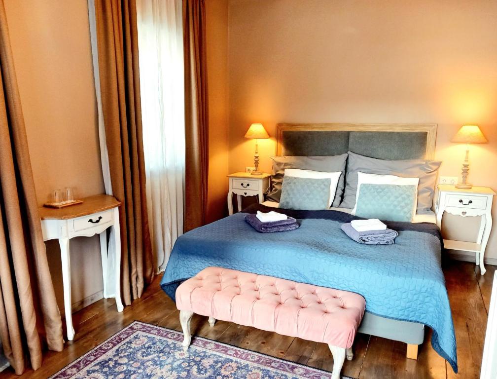 a bedroom with a blue bed with a pink bench at Őri Art Inn in Őriszentpéter