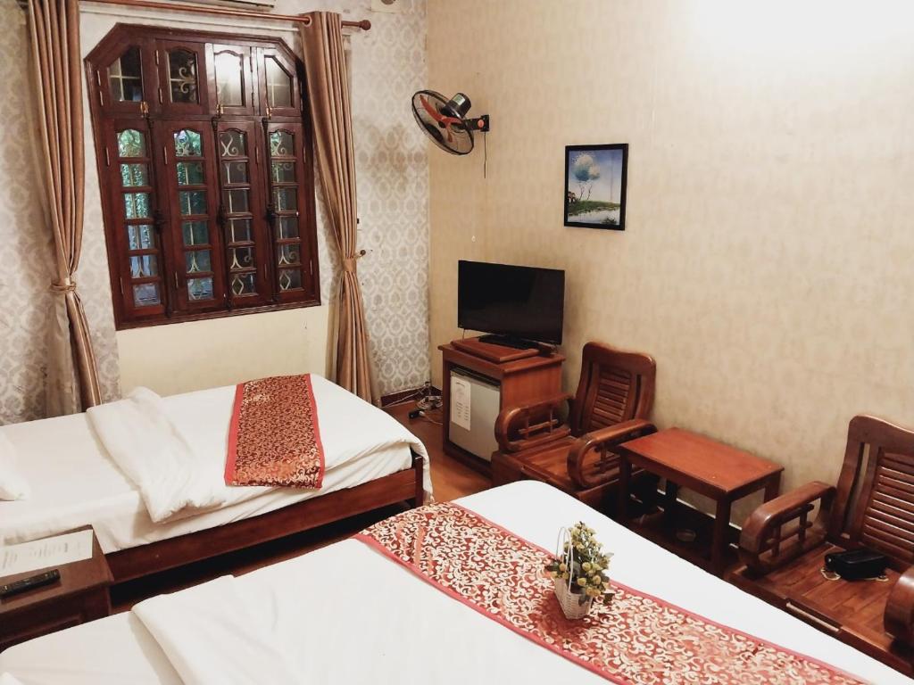 a room with two beds and a television and a chair at Holiday home in Hanoi