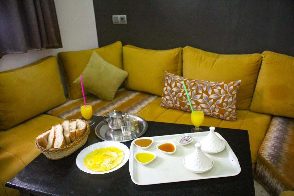 um sofá com uma mesa com uma bandeja de ovos e bebidas em Equinox em Tan-Tan Plage