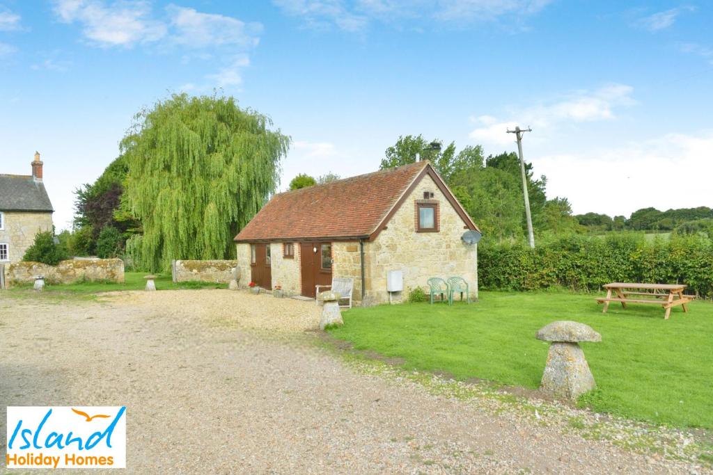 ein kleines Haus auf einem Feld mit einem Rasenplatz in der Unterkunft Willows in Calbourne