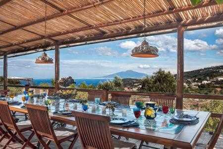 stół jadalny z krzesłami i widokiem na ocean w obiekcie GOCCE VILLAS - Antica Limonaia w mieście Massa Lubrense