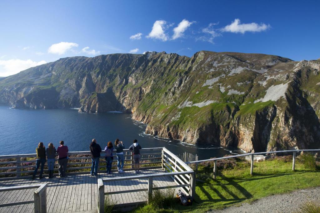 a group of people standing on a boardwalk looking at the ocean at Glencolumbkille House - Self Catering Rooms in Glencolumbkille
