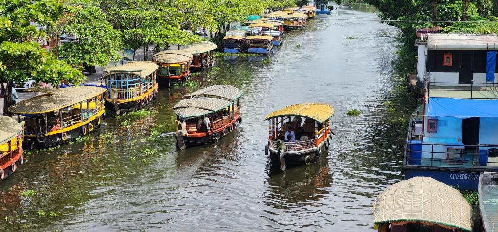 um grupo de barcos em um rio com edifícios em 'Marari Johns Homestay' Mararikulam, Alappuzha em Alappuzha